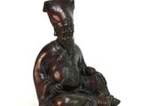 a bronze statue of a man sitting on the ground