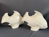 deux figurines de poissons en céramique blanche posées sur une table
