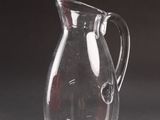 a glass pitcher sitting on a table with a shadow on the table