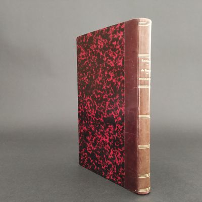 an old book sitting on top of a table with a red cover