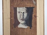 painting of a woman ' s face in a wooden frame on a stand