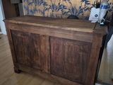 a wooden cabinet in the middle of a room with a wallpaper behind it