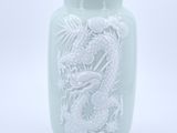 a green vase with a dragon on it on a white background