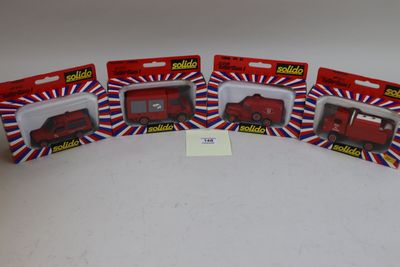 Quatre camions rouges miniatures sont alignés sur une surface blanche