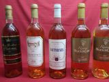 six bottles of wine are lined up in a row on a pink background