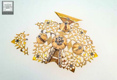 a picture of a gold brooch and earrings on a white surface