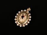 un gros plan sur un pendentif en or orné de perles et d'une pierre rouge