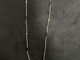 a close up of a necklace with a butterfly on it on a black surface