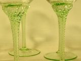 three green wine glasses sitting on top of a table next to each other