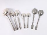 six spoons and a spoon rest on a white surface