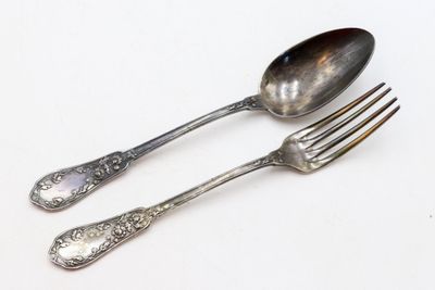 deux cuillères et une fourchette en argent sur une surface blanche