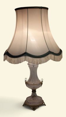 une lampe posée sur une table, avec un abat-jour blanc