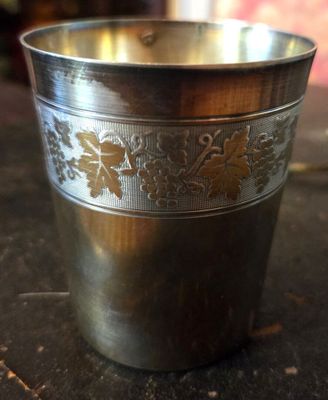 une tasse en métal ornée d'un motif, posée sur une table