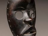 a close up of a wooden mask on a metal stand