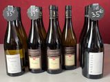 Des bouteilles de vin sont alignées sur un comptoir devant un mur rouge