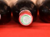 four bottles of wine are lined up on a red surface