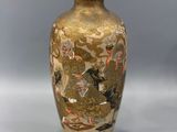 a gold vase with birds on it sitting on a table