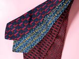 three different colored ties on a pink background
