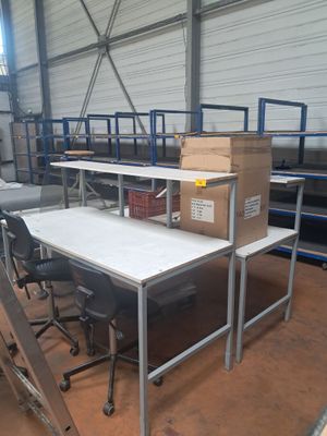 des tables et des chaises dans un entrepôt, avec des cartons empilés dessus