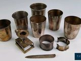 de nombreuses tasses en argent et un couteau posés sur une table