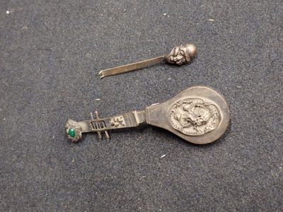 une cuillère en argent et une petite cuillère en argent par terre