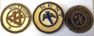 three badges of different colors and designs on a white surface