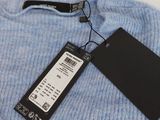 a close up of a blue sweater with a tag on it