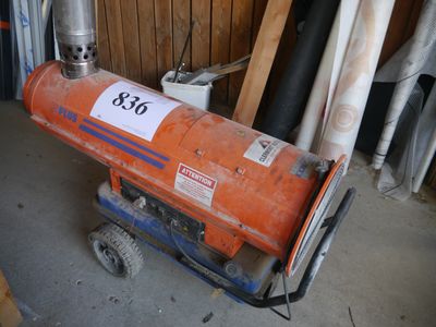 an orange gas heater sitting on a cart in a garage