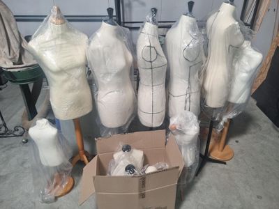 many mannequins in a cardboard box on the floor
