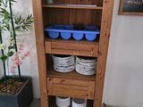 a tall wooden shelf with dishes and cups on it