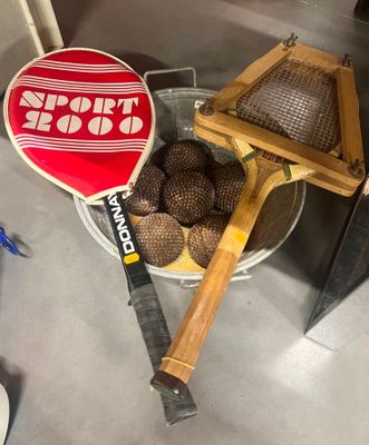 une raquette de tennis et quelques balles dans un seau