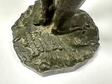 a bronze statue of a person standing on a rock