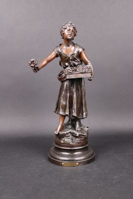 statue en bronze représentant une femme tenant un panier de fleurs, posée sur un socle