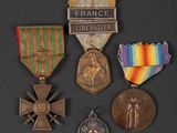 three medals and a cross are on a black surface
