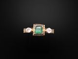 une bague sertie d'une émeraude et d'une perle sur fond noir