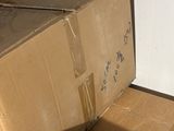 une boîte en carton posée sur le sol à côté d'un mur