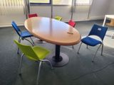 brightly colored chairs sit around a round table in an empty room