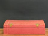 an old red box sitting on top of a wooden table