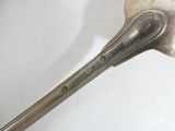 a silver spoon with a handle on a white surface