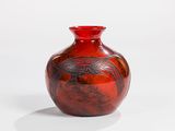 a red vase sitting on a white surface with a bird on it