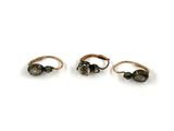 three gold rings with black stones on them on a white surface