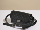 the black quilted bag is sitting on a white table