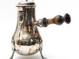 an antique silver coffee pot with a wooden handle on a white background