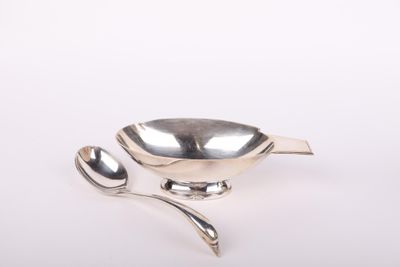 une image représentant une cuillère en argent et un repose-cuillère posés sur une surface blanche