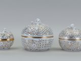 quatre objets en porcelaine décorés d'argent et d'or sur un fond gris