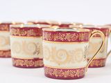 four red and gold coffee cups sitting on top of a white table