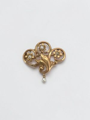 a close up of a gold brooch with pearls on it