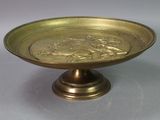 a gold plate with a design on it sitting on a stand