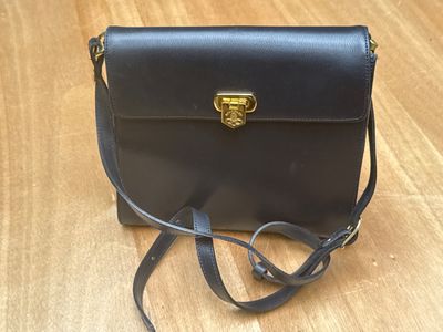 sac à bandoulière en cuir noir avec des finitions dorées et une bandoulière dorée