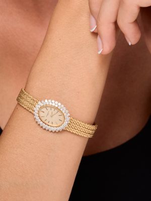 the woman is wearing a gold bracelet with a diamond watch on her wrist